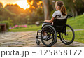 young woman sits in a wheelchair wearing headphones and listening to music. 125858172
