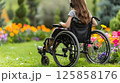 young woman sits in a wheelchair wearing headphones and listening to music. 125858176