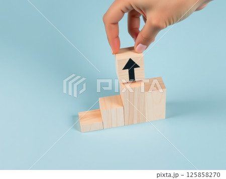 Hand Stacking Wooden Blocks with Upward Arrows 125858270