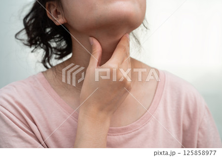 Asian woman touching her neck and throat for thyroid gland problem. 125858977