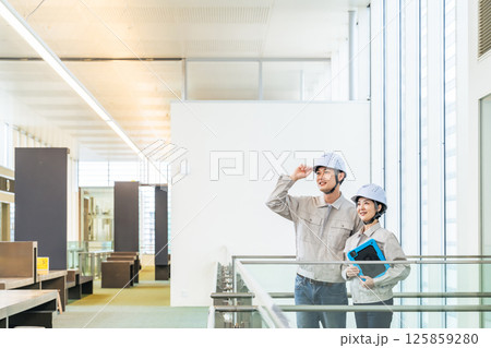 タブレットPCを持ってビルの屋内に立つ男女エンジニア 125859280