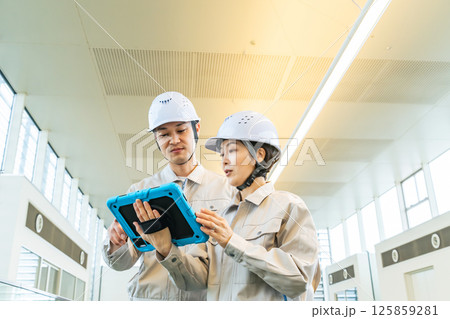 タブレットPCを見ながらビルの室内を点検する男女エンジニア タブレットPCを見ながらビルの室内を点検する男女エンジニア 125859281