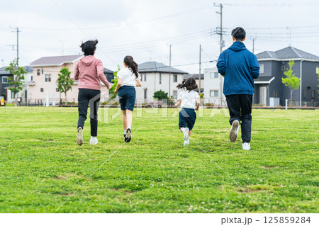芝生の公園を走る家族の後ろ姿 芝生の公園を走る家族の後ろ姿 125859284