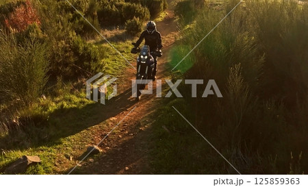 Man, professional motorcyclist in full moto equipment riding crops enduro bike on mountain road at sunset. Concept of motosport, speed, hobby, journey, activity Man, professional motorcyclist in full moto equipment riding crops enduro bike on mountain road at sunset. Concept of motosport, speed, hobby, journey, activity 125859363