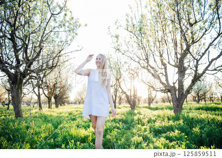 woman in summer dress walking in blooming garden in spring woman in summer dress walking in blooming garden in spring 125859511