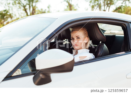 Woman driver driving a white sports car on the road Woman driver driving a white sports car on the road 125859657