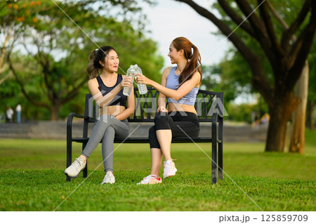 Cheerful female friends resting together after exercising outdoors Cheerful female friends resting together after exercising outdoors 125859709