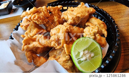 Crispy Deep-Fried Chicken Bites with Fresh Lime Garnish Crispy Deep-Fried Chicken Bites with Fresh Lime Garnish 125861286