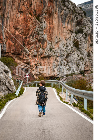 Boy Walking a Trail Beside Cliffs Overlooking Olive Grove 125861396
