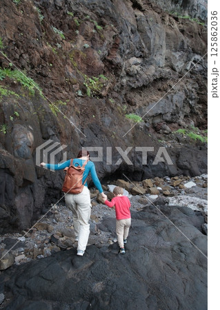 Mother and son exploring volcanic caves holding hands Mother and son exploring volcanic caves holding hands 125862036