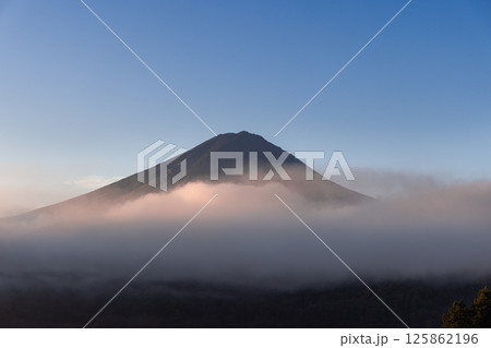 Golden morning light casts a warm glow on the mist surrounding Mount Fuji Golden morning light casts a warm glow on the mist surrounding Mount Fuji 125862196