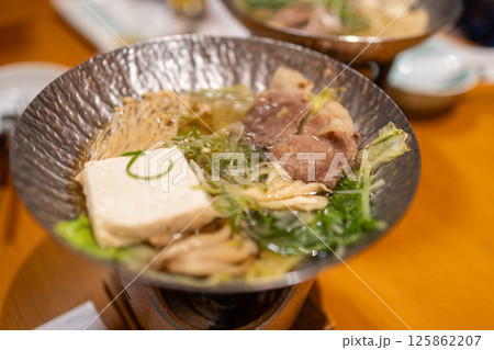 Japanese hot pot dish with beef, tofu, enoki mushrooms and greens simmering in a light broth 125862207