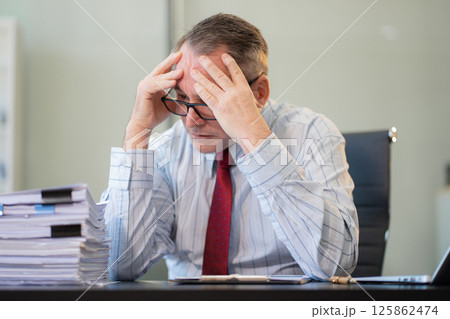 Stressed caucasian maturebusinessman working in the office. Stressed caucasian maturebusinessman working in the office. 125862474