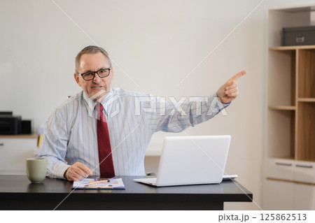 Happy Mature businessman presenting or pointing, happy working.small business owner working online. Happy Mature businessman presenting or pointing, happy working.small business owner working online. 125862513