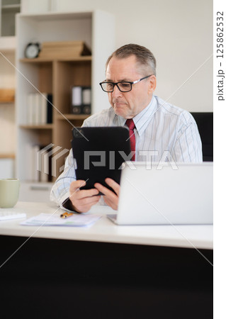 Mature businessman working online from home, small business lifestyle. Mature businessman working online from home, small business lifestyle. 125862532