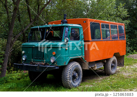 Old off-road truck with green cabin and orange passenger body 125863883