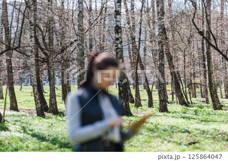 A fashionable lady is walking in a spring park. Blurred foreground.  125864047