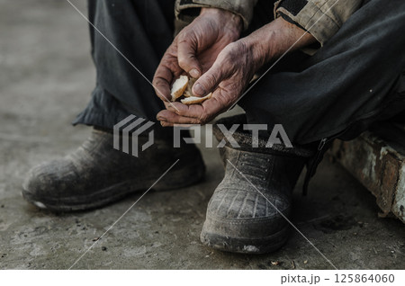 The tired hands clutch the crumbs as if they were precious. The hands are cracked from years of labor. 125864060