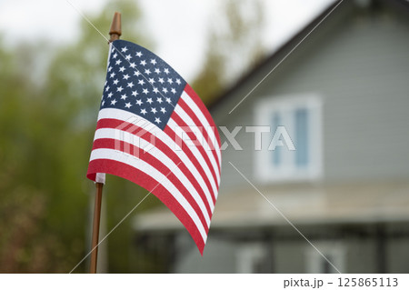 American flag in front of suburban house. American Independence Day patriotic decoration. Freedom and national pride in summer. Outdoors American flag in front of suburban house. American Independence Day patriotic decoration. Freedom and national pride in summer. Outdoors 125865113