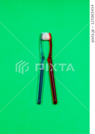 A Red toothbrush and azun facing each other on a green surface. 125865454