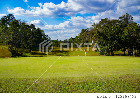 Golfer playing golf in the evening golf course, on sun set evening time. 125865455