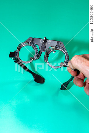 Man Hand Holding A Pair of Test Glasses on a Green Table 125865460