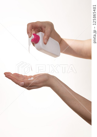 Gently applying lotion from a bottle as part of a skincare routine for healthy skin care 125865481