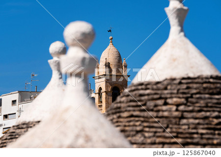 Trulli rooftops with bell tower in the background 125867040