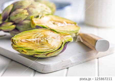 Ripe artichokes plant on white cutting board. Ripe artichokes plant on white cutting board. 125867211