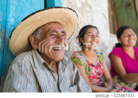 Mexican family smiling together at home with elderly man in sombrero and happy girls 125867331