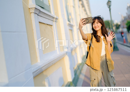Southeast asian woman takes selfie while travel exploring city street, capturing joyful moment that reflects travel concept and her happy expression Southeast asian woman takes selfie while travel exploring city street, capturing joyful moment that reflects travel concept and her happy expression 125867511