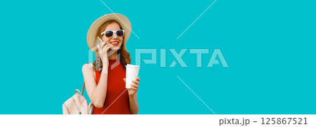Happy cheerful young woman calling on phone with cup of coffee in tourist hat with backpack Happy cheerful young woman calling on phone with cup of coffee in tourist hat with backpack 125867521