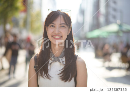 Southeast asian woman smiling outdoors in city street with sunlight and blurred background showing happiness and casual style Southeast asian woman smiling outdoors in city street with sunlight and blurred background showing happiness and casual style 125867586