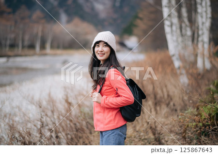 Southeast asian woman wearing warm hat and jacket enjoys travel in nature with backpack, capturing concept of adventure and peaceful outdoor exploration Southeast asian woman wearing warm hat and jacket enjoys travel in nature with backpack, capturing concept of adventure and peaceful outdoor exploration 125867643