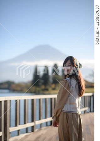 Southeast asian woman enjoys travel concept by lake with mountain view wearing headscarf and beige outfit smiling happily in peaceful outdoor setting Southeast asian woman enjoys travel concept by lake with mountain view wearing headscarf and beige outfit smiling happily in peaceful outdoor setting 125867657