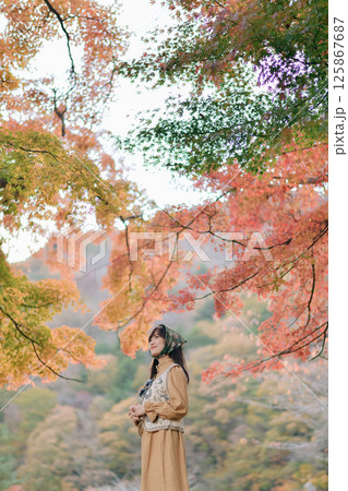 Southeast asian woman enjoys travel concept in autumn forest surrounded by colorful leaves creating peaceful and inspiring atmosphere for reflection and adventure 125867687