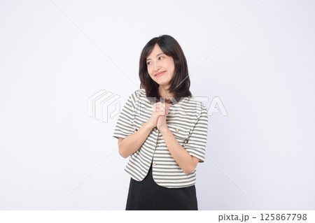 Southeast asian woman smiling gently with hands clasped in thoughtful pose for advertising on plain white background 125867798