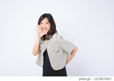 Southeast asian woman smiling brightly while advertising with cheerful gesture wearing striped jacket over black dress Southeast asian woman smiling brightly while advertising with cheerful gesture wearing striped jacket over black dress 125867803
