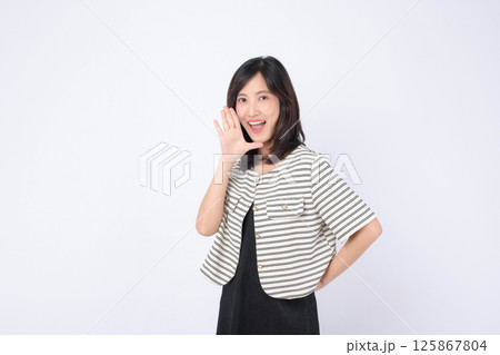 Southeast asian woman smiling and advertising with cheerful expression wearing striped jacket and black dress on white background Southeast asian woman smiling and advertising with cheerful expression wearing striped jacket and black dress on white background 125867804