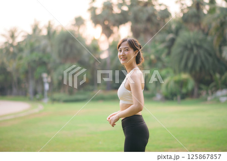 Southeast asian woman enjoying wellness and healthy lifestyle concept while doing exercise outdoors in park with joyful and relaxed expression in natural sunlight 125867857