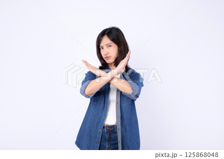 Southeast asian woman wearing denim makes advertising gesture with crossed arms showing refusal or stop in confident pose 125868048