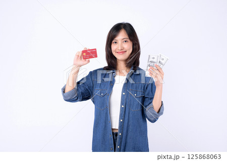 Southeast Asian woman smiling holding credit card and cash money showing internet banking and mobile payment application concept for financial transaction and digital economy 125868063