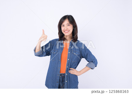 Southeast Asian woman smiling and giving thumbs up wearing denim jacket and orange shirt for advertising concept with positive emotion 125868163