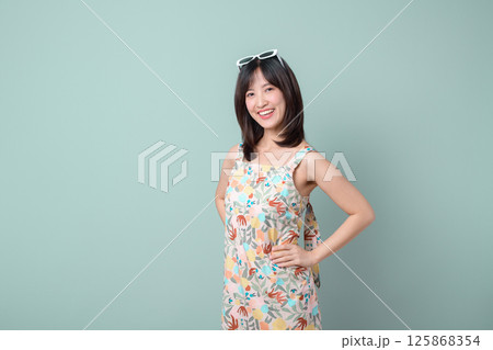 Southeast asian woman smiles confidently wearing colorful dress and sunglasses showing creative spirit as small business owner in retail and online store startup industry shopping 125868354