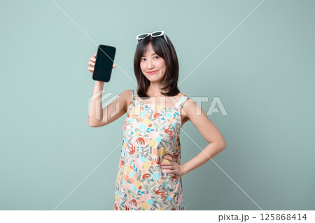 Southeast asian woman smiles confidently while holding mobile phone showing internet application on plain background, expressing ease and modern connectivity Southeast asian woman smiles confidently while holding mobile phone showing internet application on plain background, expressing ease and modern connectivity 125868414