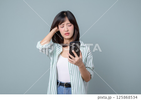 Southeast asian woman using mobile phone with worried expression while browsing internet application in casual outfit 125868534