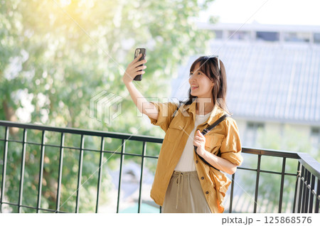 Southeast asian woman enjoys travel concept by taking selfie outdoors with bright natural background and joyful expression on her face Southeast asian woman enjoys travel concept by taking selfie outdoors with bright natural background and joyful expression on her face 125868576