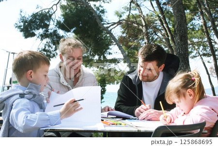 happy family doing homework outside in cafe, lifestyle people happy family doing homework outside in cafe, lifestyle people 125868695