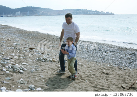 young father playing with his son with rock on beach, happy lifestyle family 125868736
