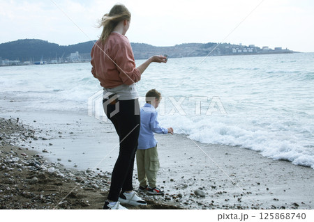 young mother playing with her son with rock on beach, happy lifestyle family young mother playing with her son with rock on beach, happy lifestyle family 125868740